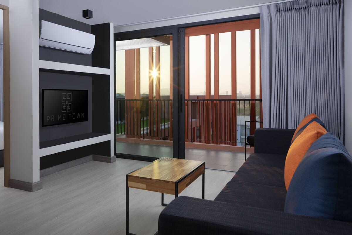 A modern living room with a flat-screen TV, a wooden coffee table, and a sofa with cushions.