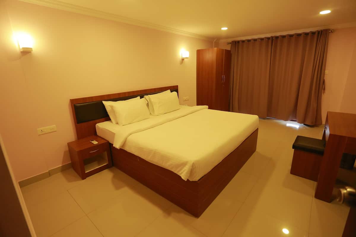 A hotel room with a large bed, a wardrobe, a nightstand, and a desk.
