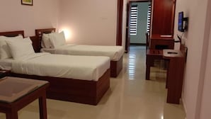 Una habitación de hotel con dos camas individuales, un escritorio, una silla y un televisor.