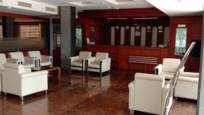 Un vestíbulo con sofás de cuero blanco, un mostrador de recepción y un reloj.