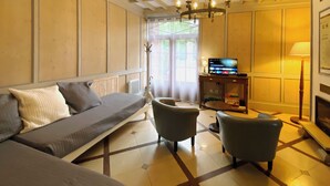Una habitación con sofá, dos sillones, televisor y candelabro.