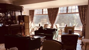 A spacious living area with a bar, comfortable seating, and large windows offering a view of the outdoors. - Brass Castle Country House Accommodation (Middlesbrough)