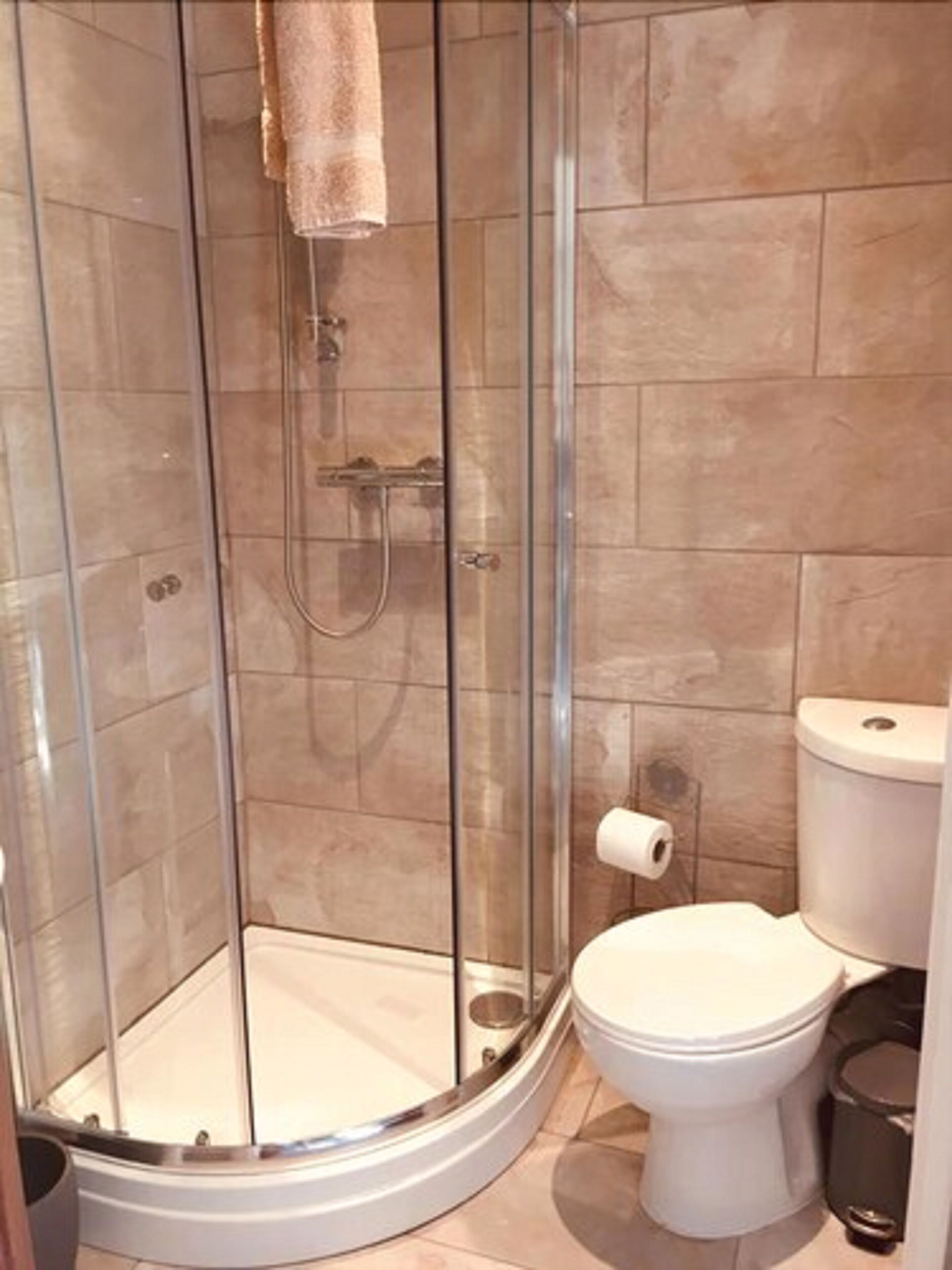 Ein modernes Badezimmer mit einer Duschkabine, einer Toilette und einem Mülleimer.