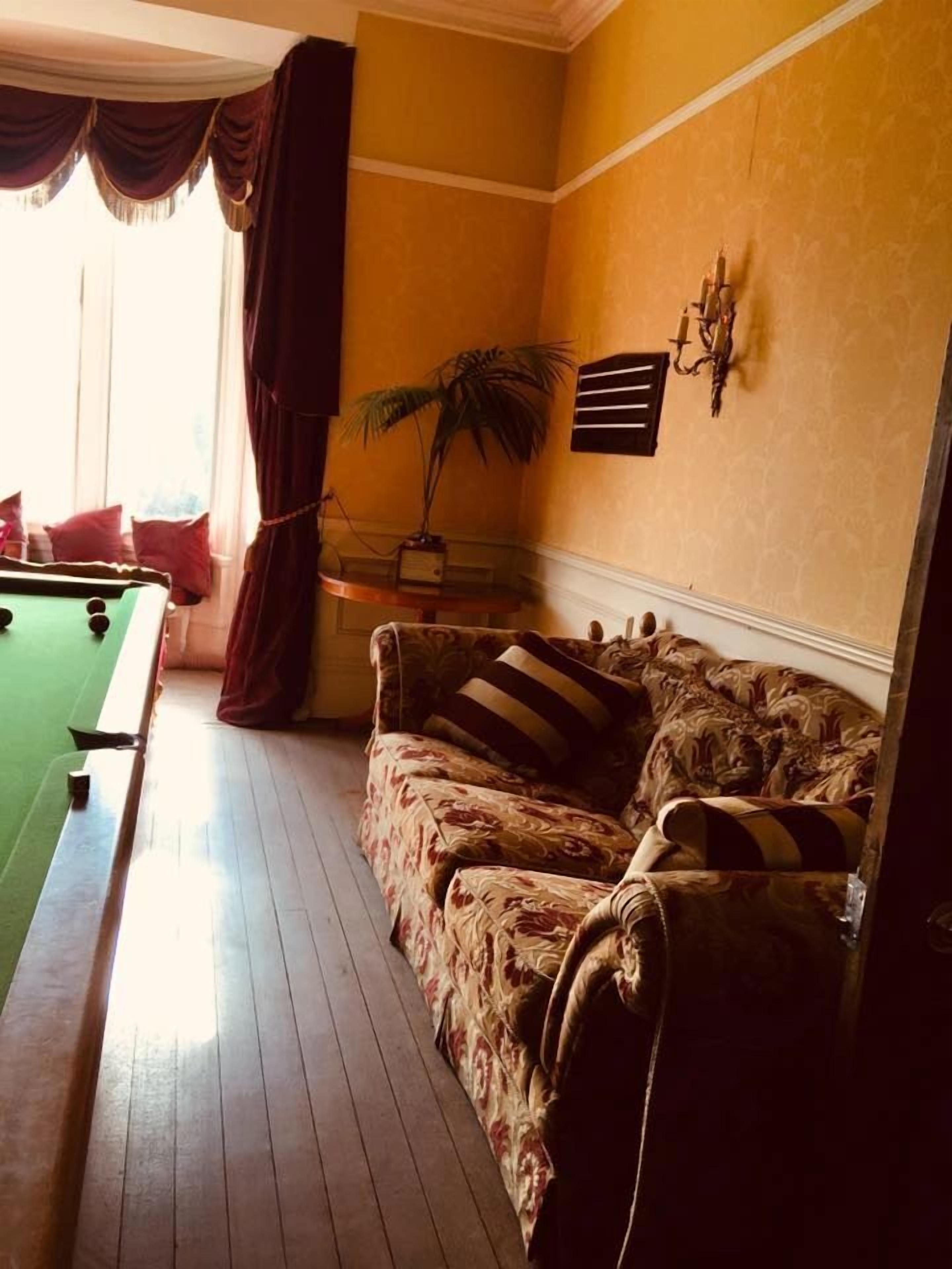 Ein Zimmer mit Pooltisch, einer Couch, einer Topfpflanze und einer Wandlampe.