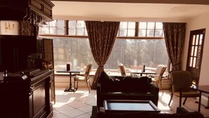 A living room with a sofa, a coffee table, a dining table with chairs, and a kitchen area with cabinets and a stove. - Brass Castle Country House Accommodation (Middlesbrough)
