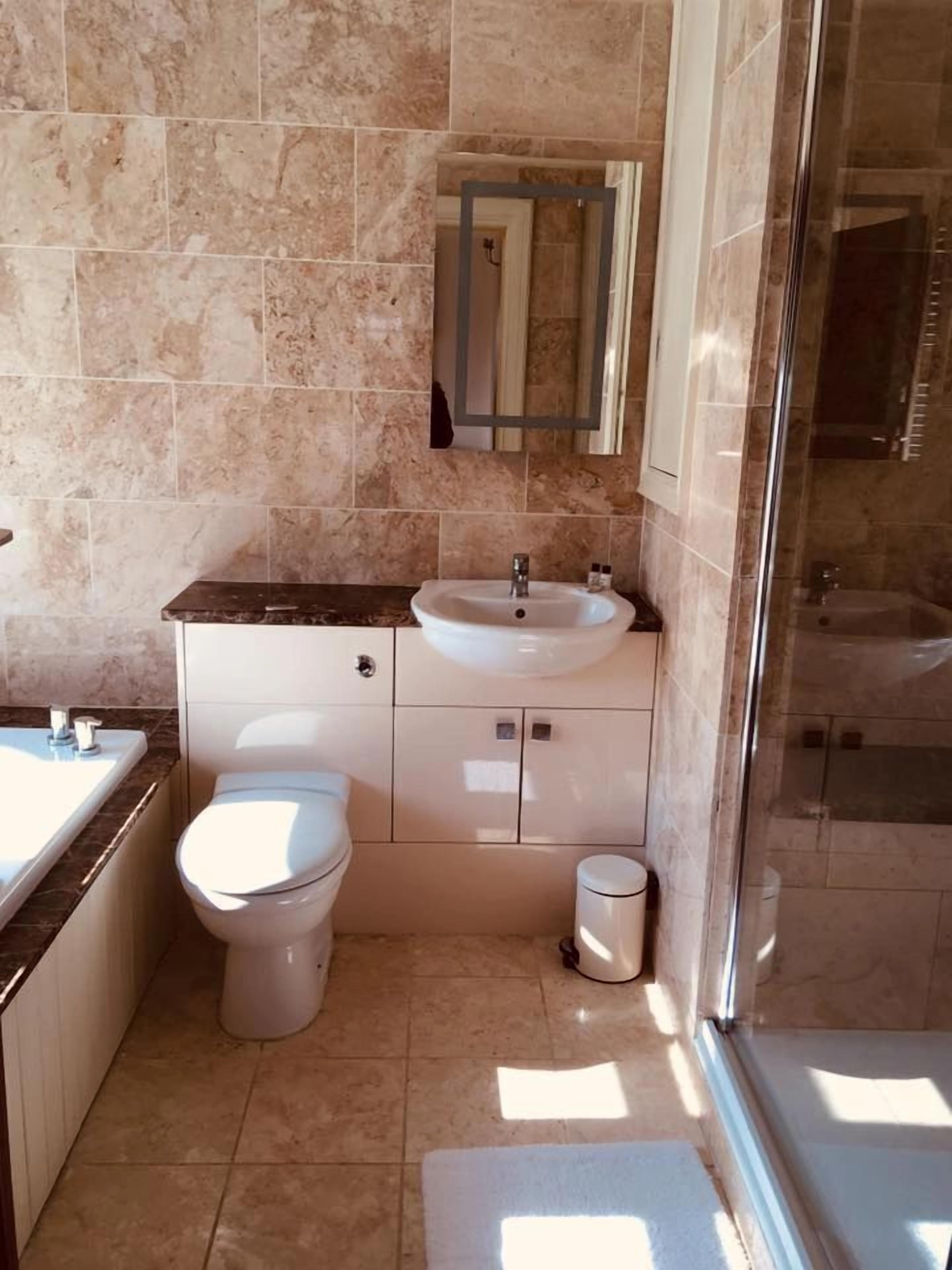 A bathroom with a sink, toilet, and a glass-enclosed shower.