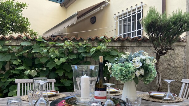 A table set outdoors with plates, glasses, a candle, and a bottle of wine. - Spacious & Bright in Lucca Country Villa  (Capannori, Lucca, Tuscany)