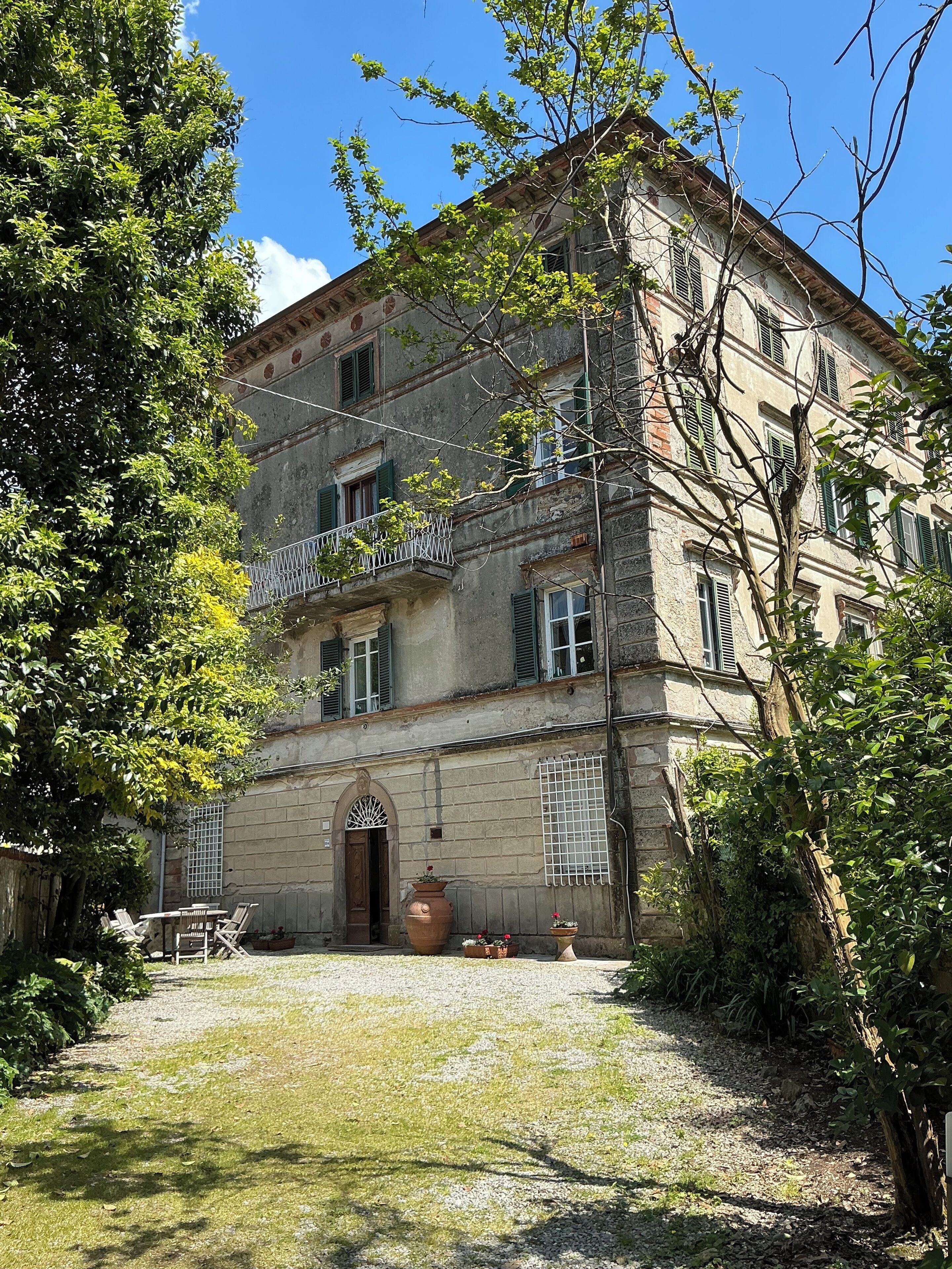Un edificio storico con un cortile interno, un'ampia entrata ad arco e un balcone con ringhiera.