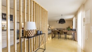 Een moderne keuken met houten lambrisering, een eethoek met tafel en stoelen, en een hangende lamp.