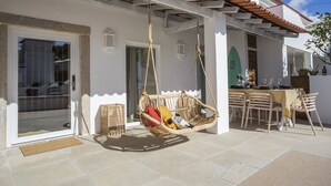 Een terras met een hangstoel, een eettafel en stoelen.