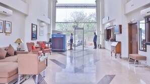Un hall d’entrée spacieux avec un plafond haut, un comptoir d’accueil, un espace salon et une vue dégagée sur l’extérieur grâce à une grande fenêtre.
