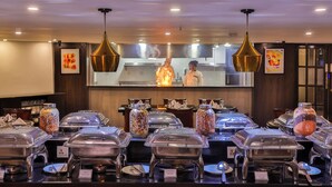 Un buffet avec des présentoirs de nourriture couverts et un espace cuisine en arrière-plan.