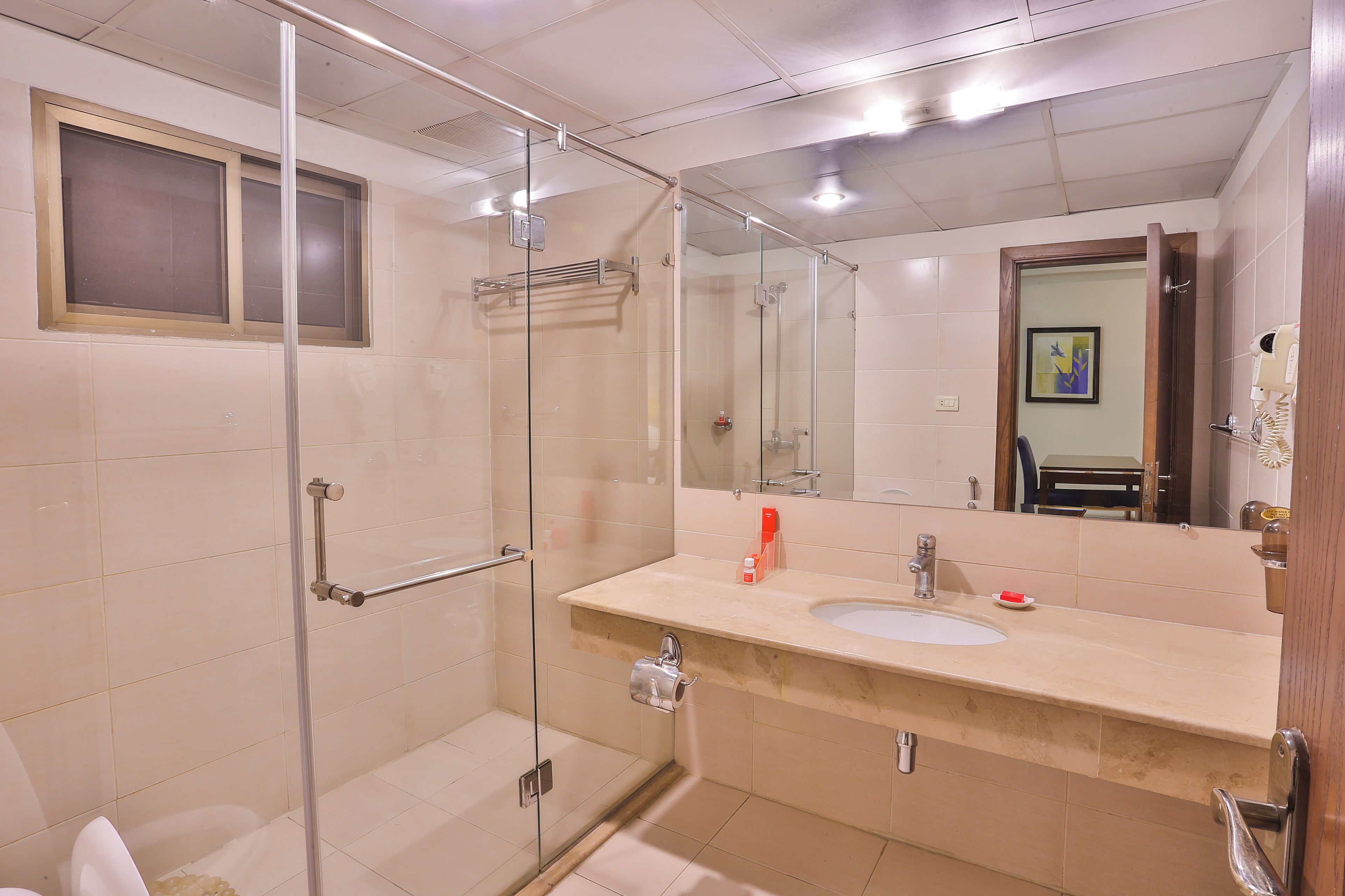 A modern bathroom with a glass shower enclosure, a sink with a mirror, and a towel rack.