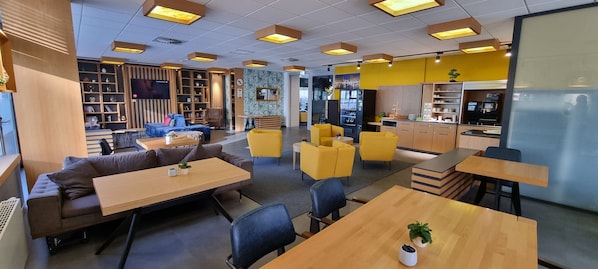Un espace de détente moderne comprenant des sièges, une cuisine et une bibliothèque.