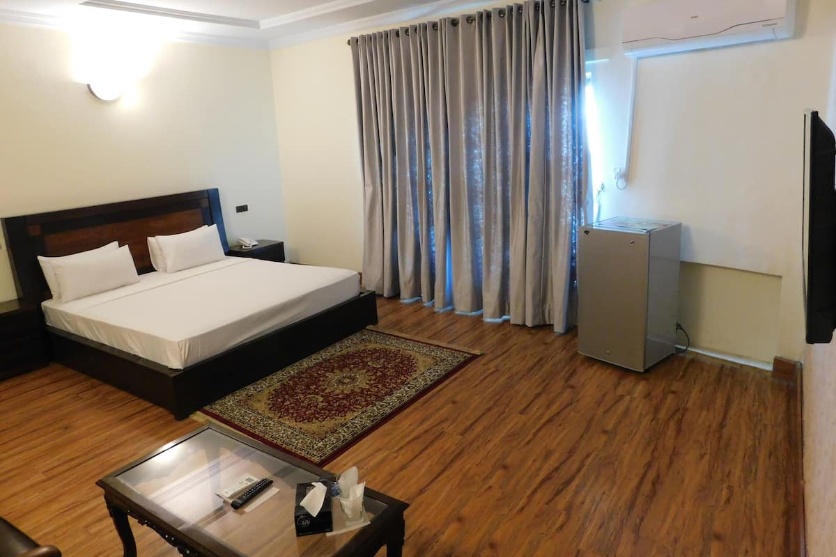 A hotel room with a bed, a desk, a television, and a window with curtains.