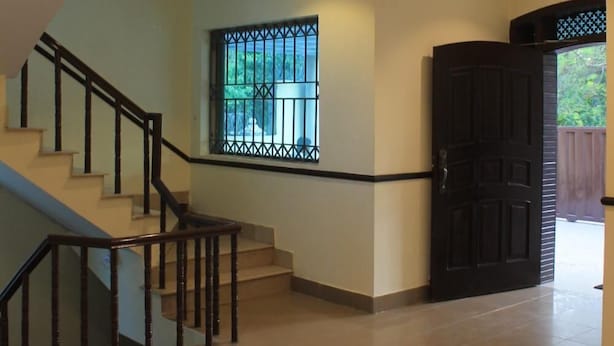 A spacious interior with a staircase, a decorative star-patterned floor, and a window with metal bars. - Sunset Destination (Islamabad)