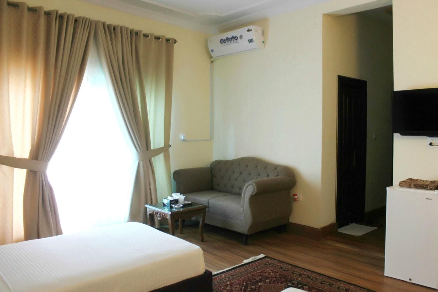 A room with a bed, a sofa, a small table, a television, and a heater.