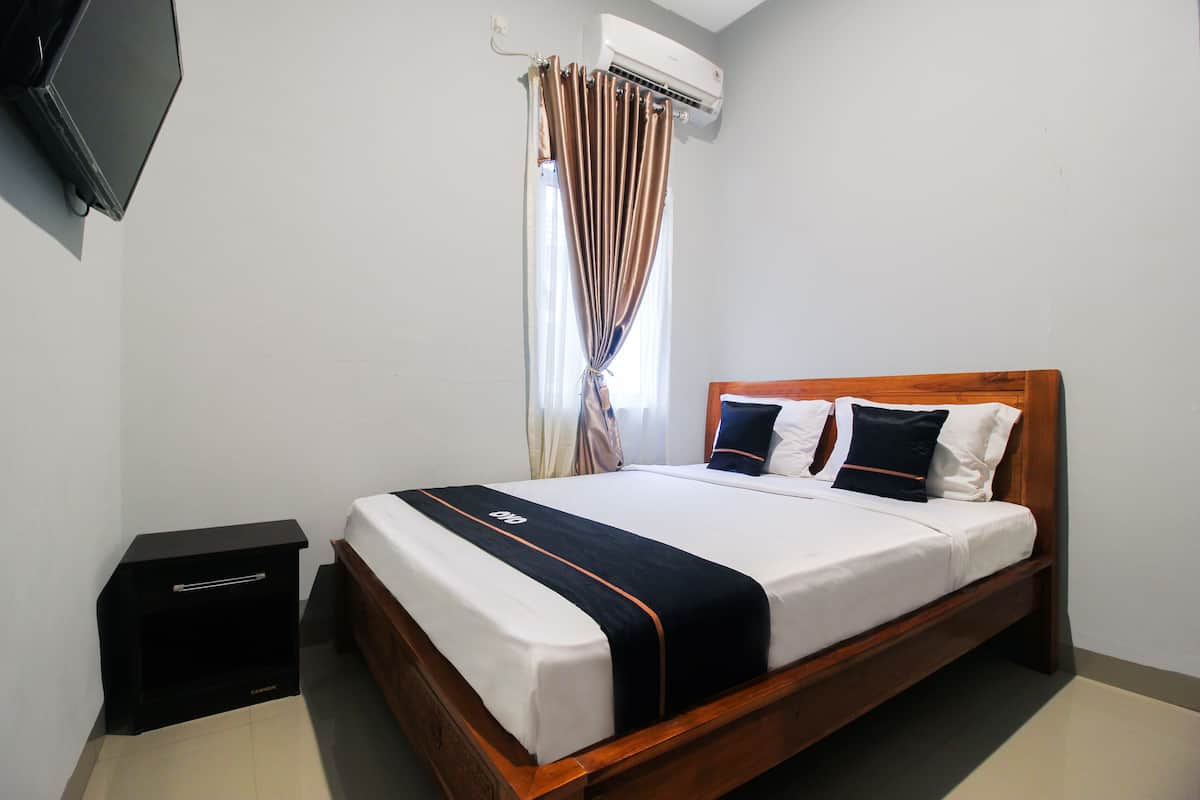A neatly made bed with a black and white bedspread, a wooden headboard, and a small bedside table.