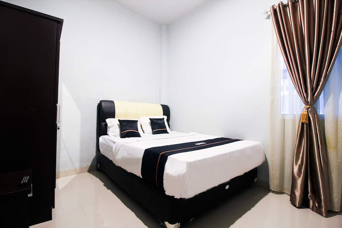 A neatly made bed with a black headboard, white bedding, and a black and white striped blanket.