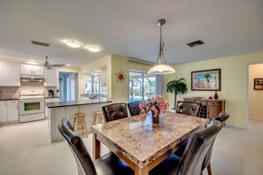A spacious kitchen with a central island, modern appliances, and a dining area with a marble table and leather chairs.