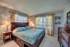 Una camera da letto con un letto grande, due lampade ai comodini, una cassettiera e una finestra con tende.