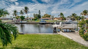 Un puerto deportivo con barcos amarrados, rodeado de casas residenciales y palmeras.