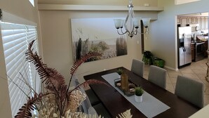 A dining area with a dark wooden table, chairs, a chandelier, and a painting on the wall. - Villa Tortuga - Place to relax (Cape Coral)