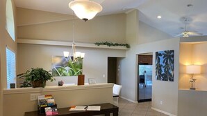 A reception area with a desk, a hanging light fixture, a potted plant, and a wall-mounted shelf with items. - Villa Tortuga - Place to relax (Cape Coral)