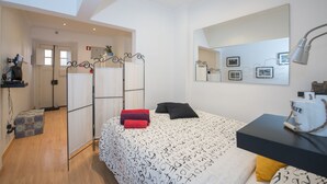 Un dormitorio con cama, escritorio, espejo y una pared con cuadros.