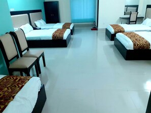 A hotel room with four beds arranged in a square layout, a desk, and a chair. - Hotel Grand Surma (Sylhet)