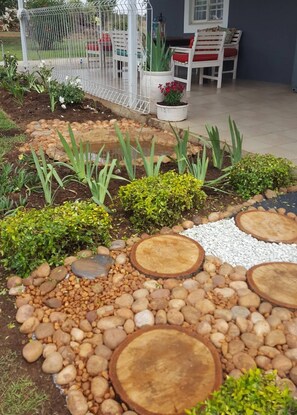 Un jardin où l’on trouve une grande variété de plantes, une clôture blanche et un espace aménagé avec une table et des chaises.