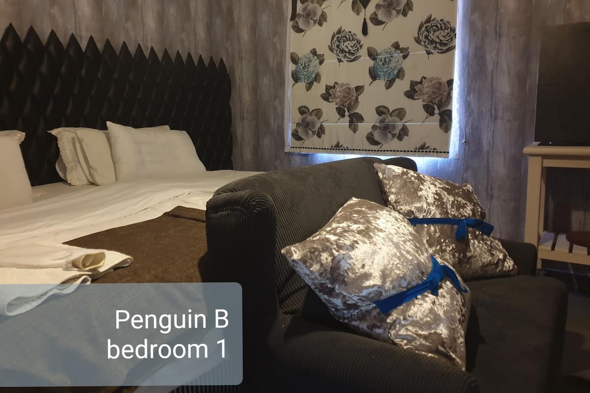 Une chambre à coucher avec un lit, un canapé et un mur recouvert d’un papier peint à motifs floraux.