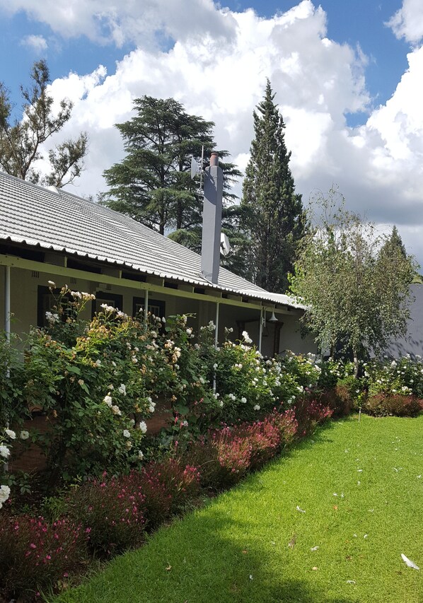 A building with a tiled roof, surrounded by lush greenery and flowering plants.