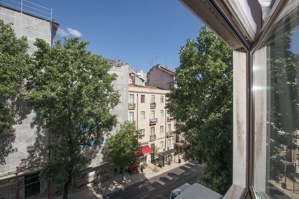 A street view with buildings, trees, and a clear sky.