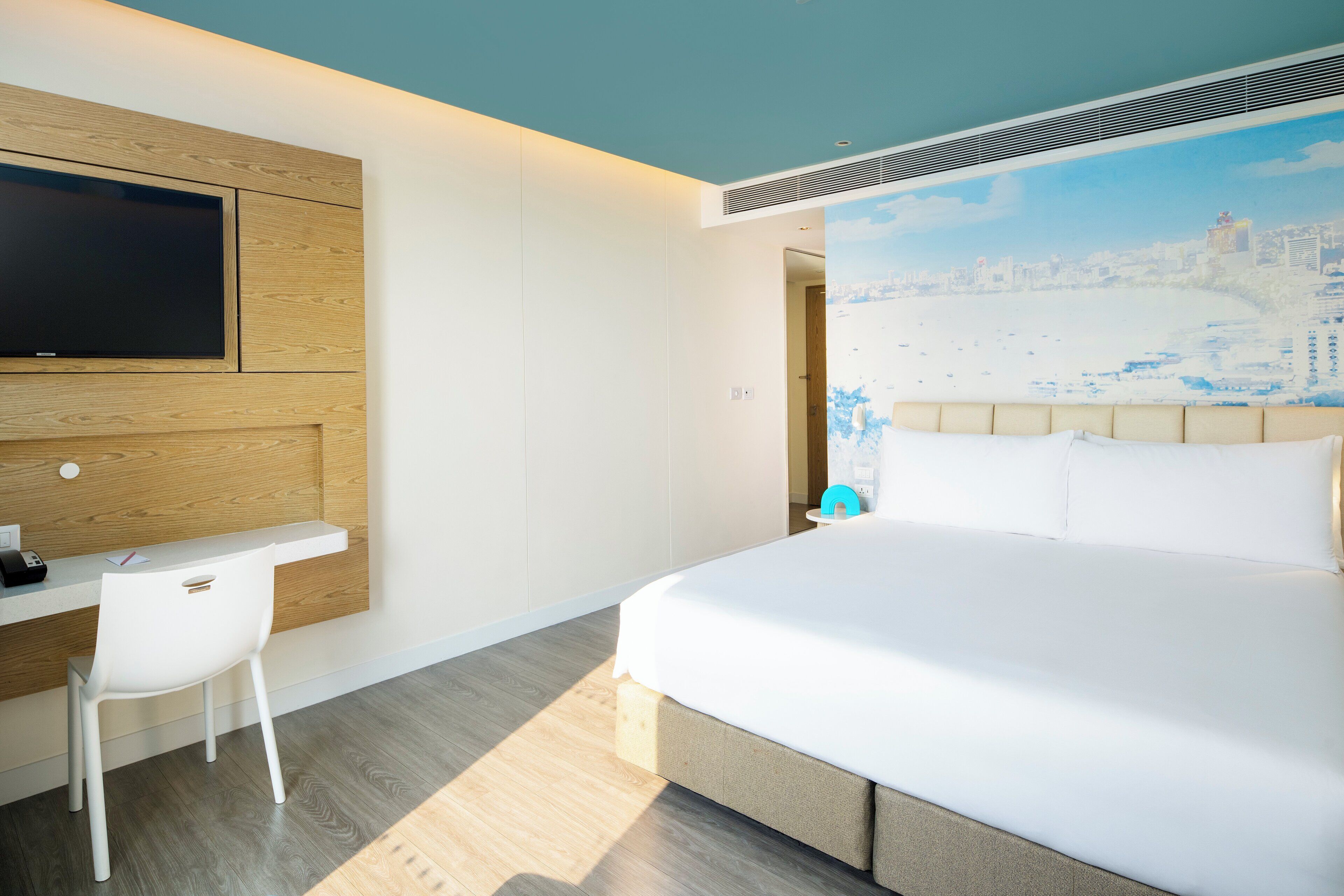 A hotel room with a bed, a desk, and a chair.