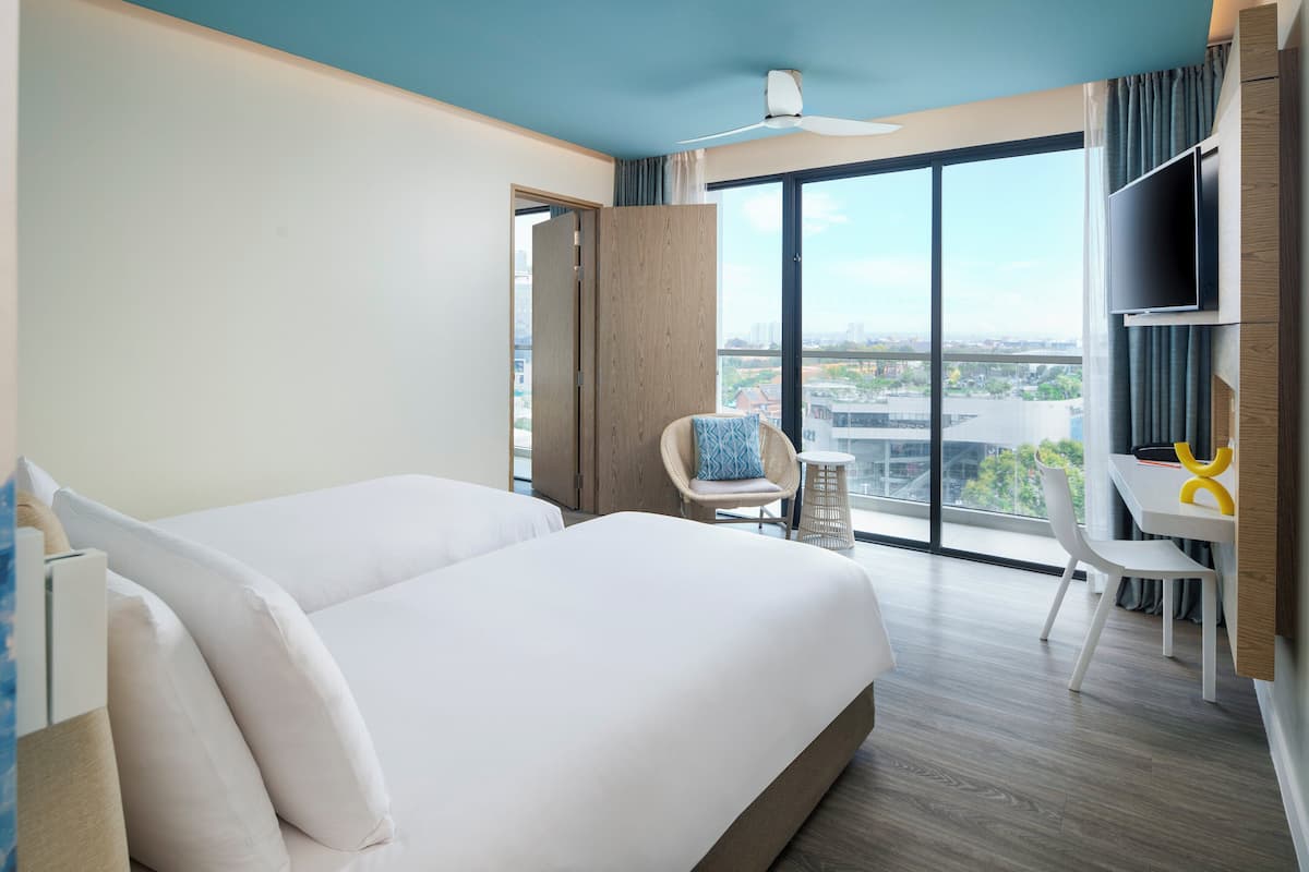 Habitación de hotel con una cama grande, un escritorio, una silla y vistas a la ciudad.