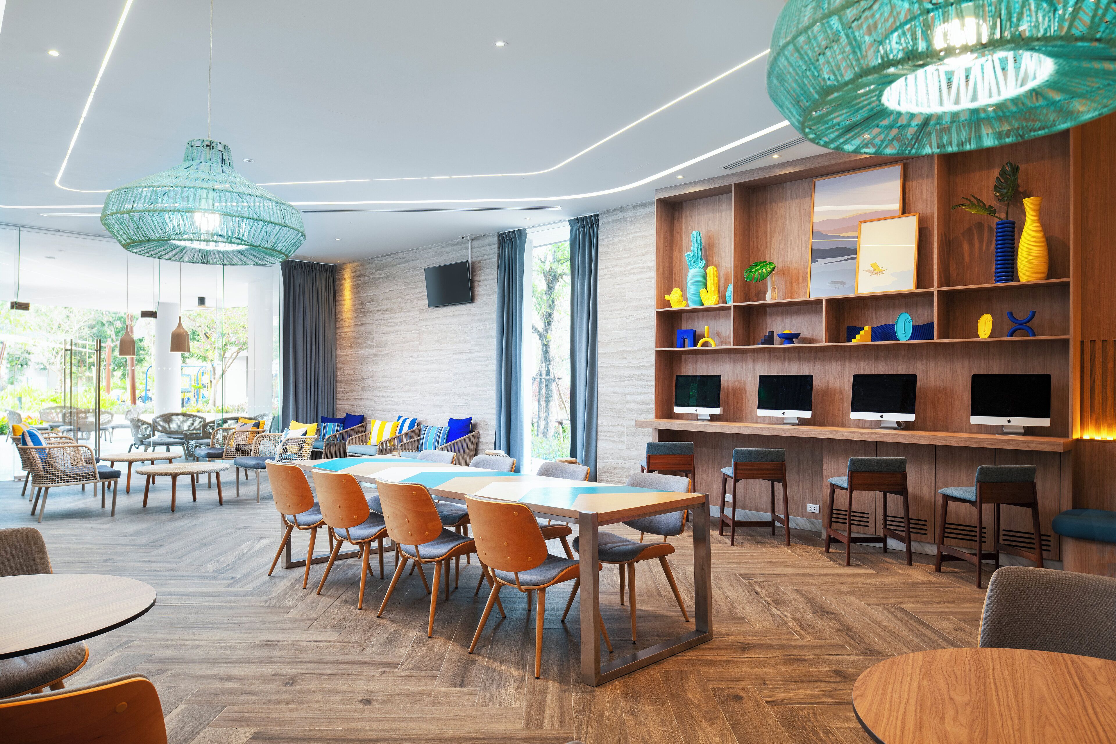 A modern dining area with wooden tables and chairs, a large hanging light fixture, and a wall-mounted TV.