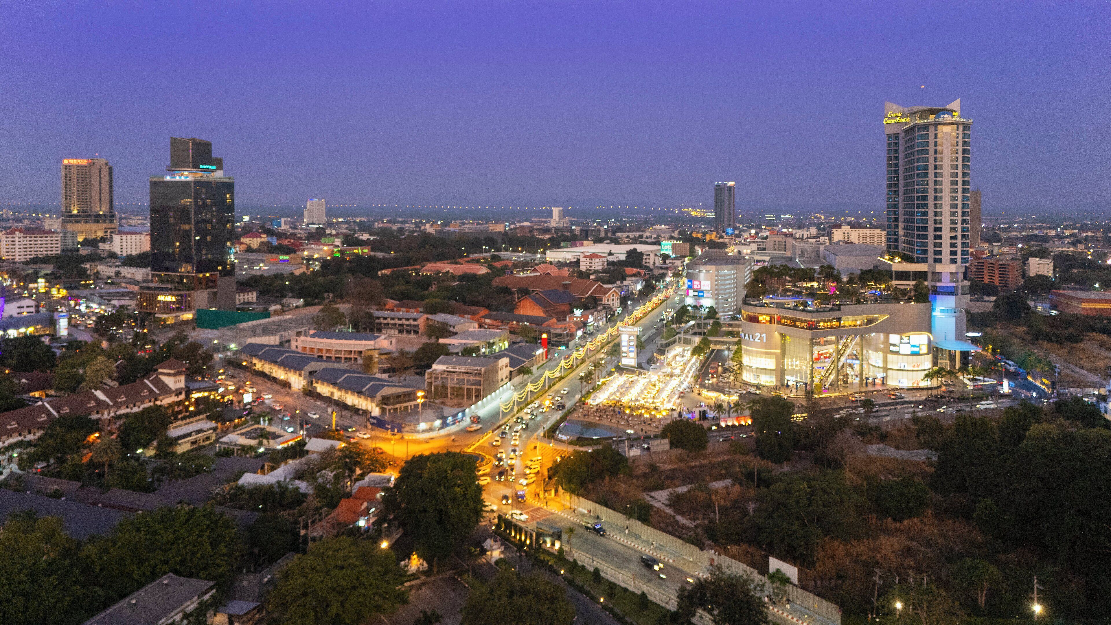 A cityscape at dusk with illuminated buildings and a busy street.