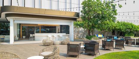 An outdoor seating area with wicker furniture and a bar.