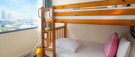 A bunk bed with a ladder, a window with a city view, and a stuffed toy.