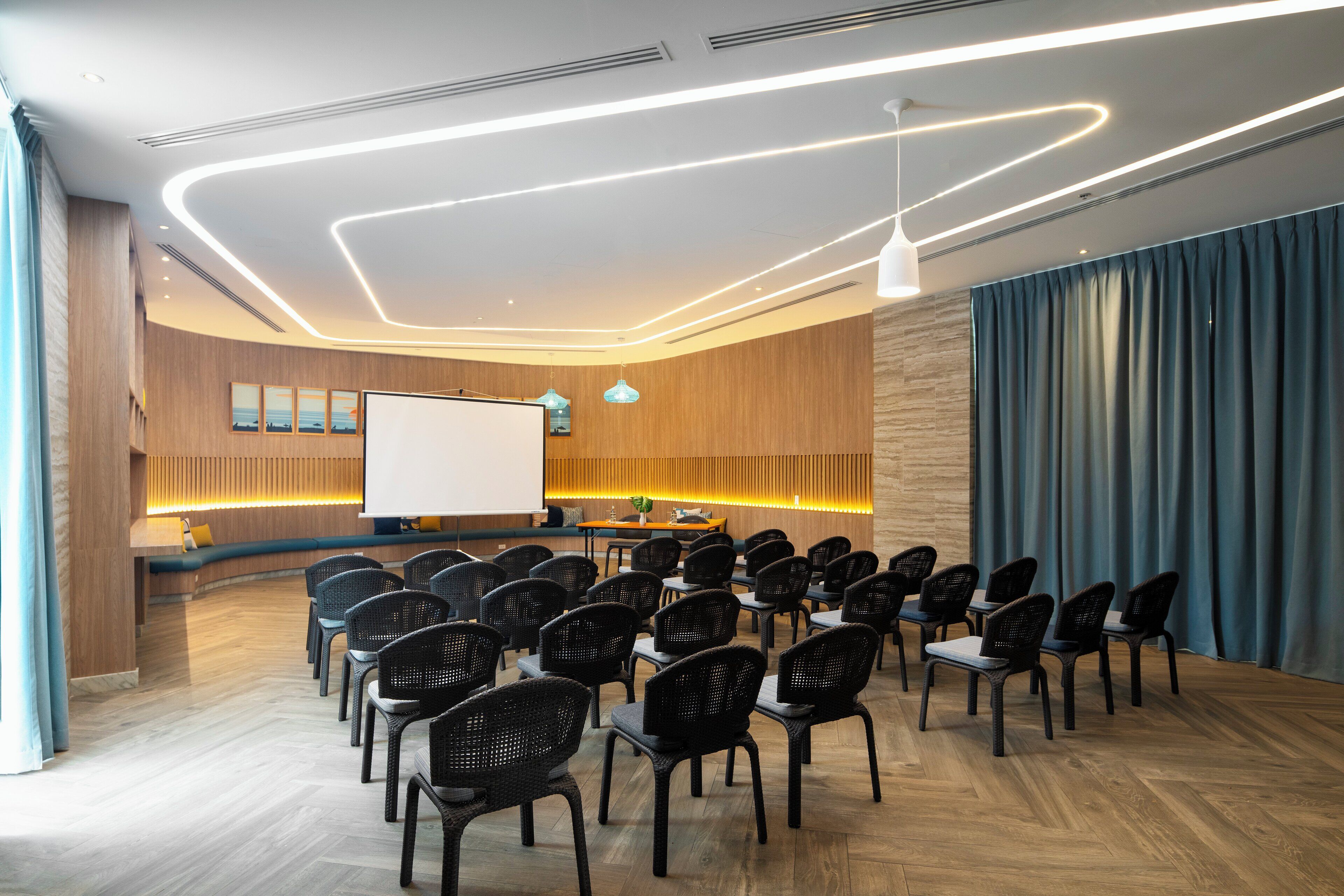 A conference room with rows of chairs, a whiteboard, and a wooden reception desk.