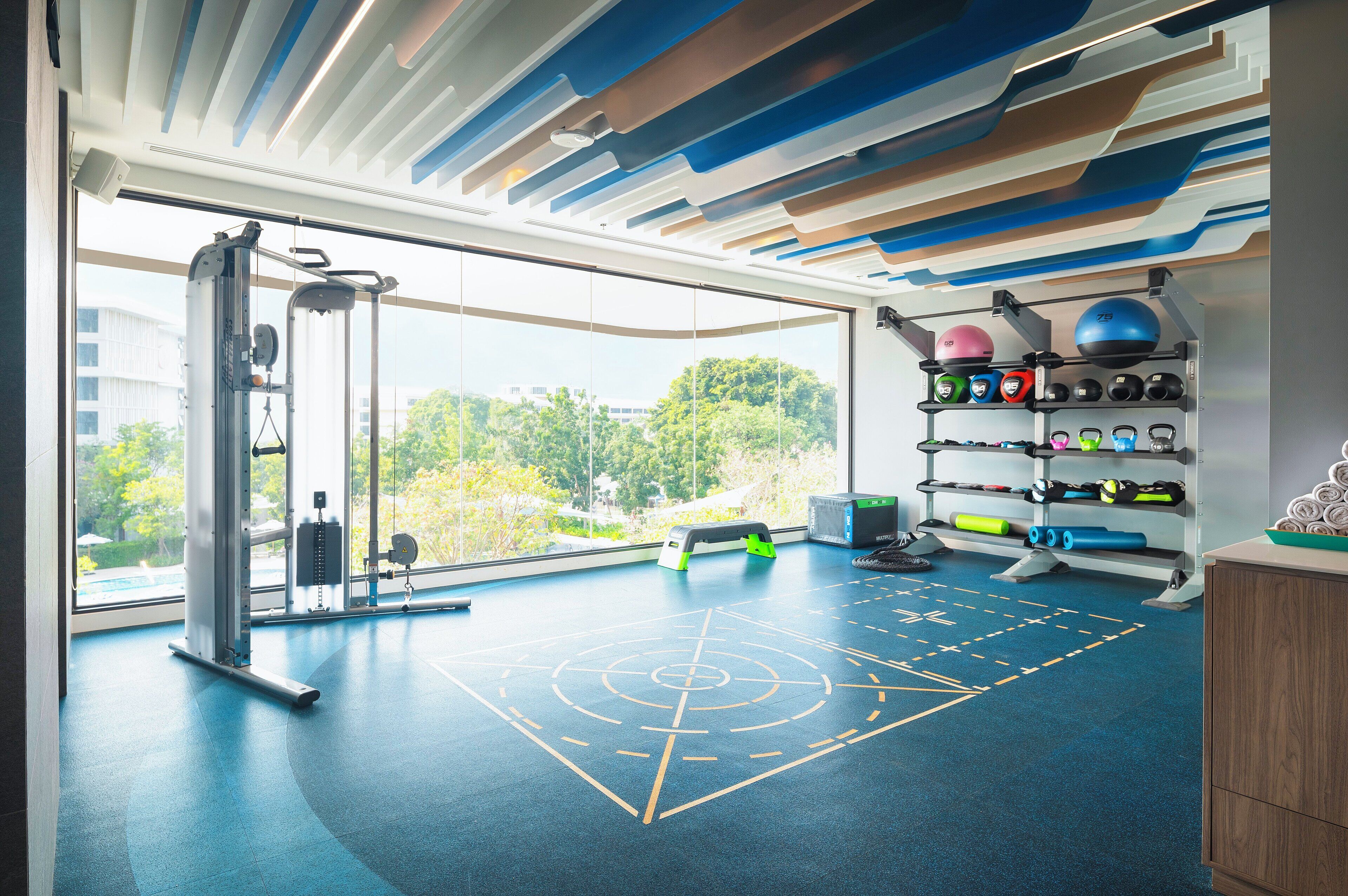 A gym with exercise equipment, a large window, and a view of greenery.