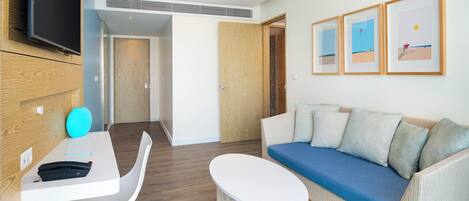 Una sala de estar moderna con un sofá blanco, una mesita redonda y un televisor de pantalla plana montado en la pared.