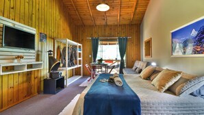 Una habitación acogedora con paredes de madera, una cama con manta azul, un televisor y un cuadro en la pared.