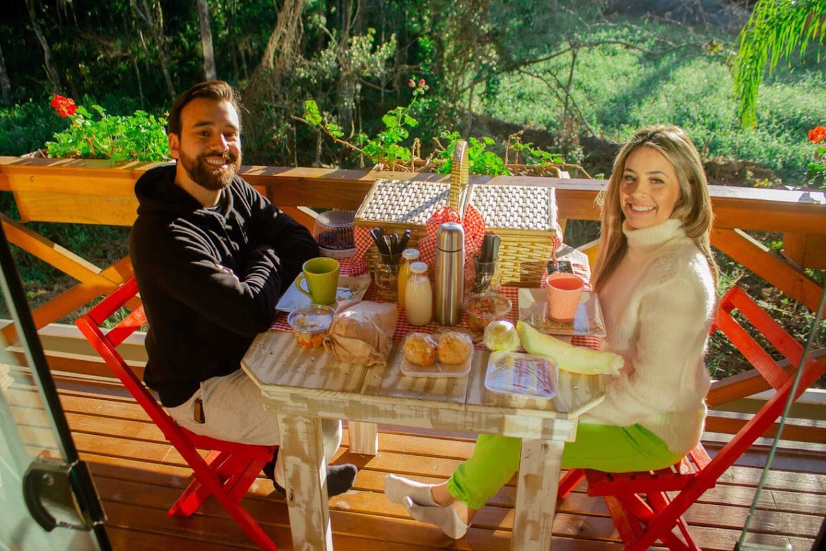 A wooden deck with a picnic table set up outdoors, surrounded by greenery.
