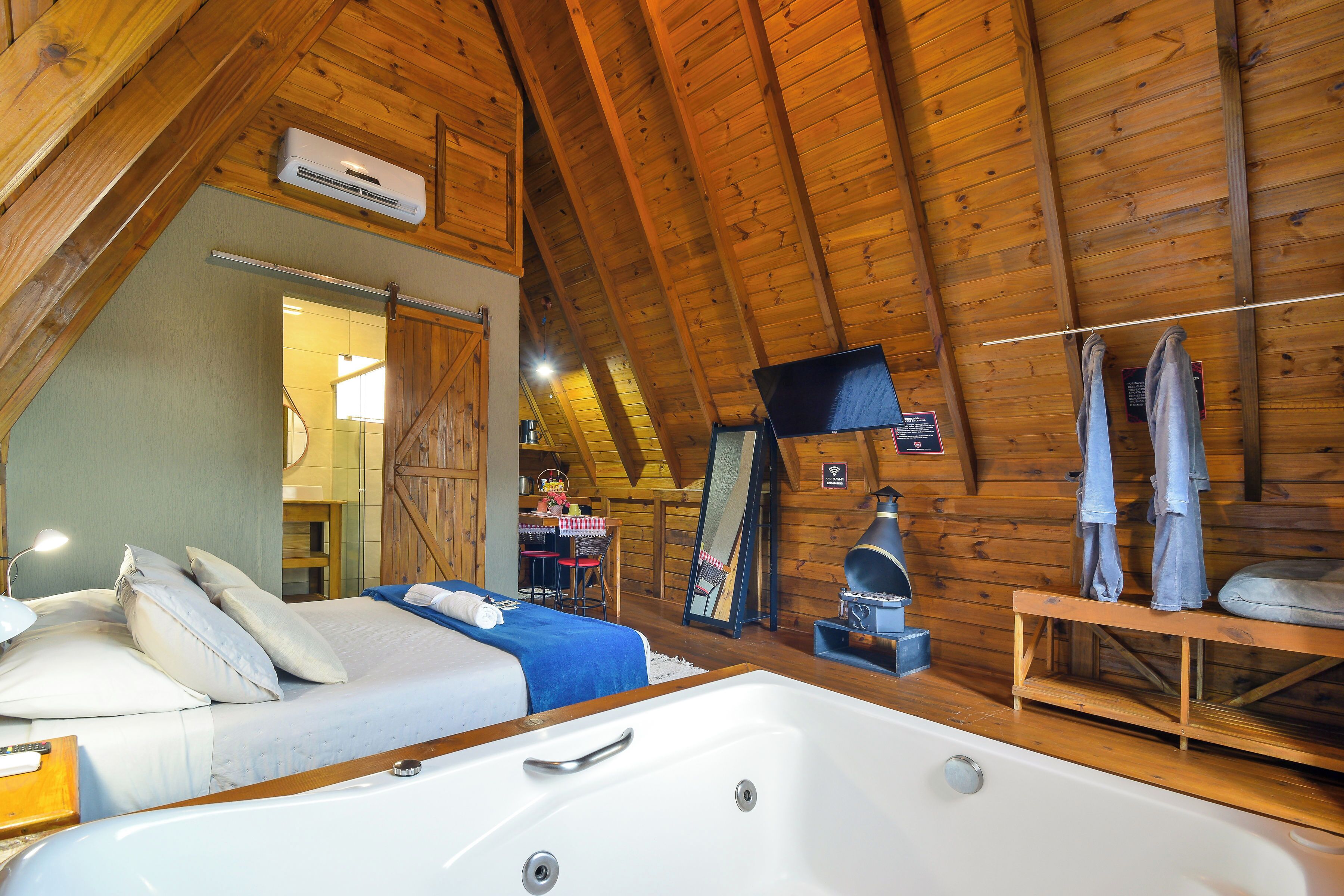 Een houten chalet inrichting met een slaapkamer, een badkamer met een groot bad en een eethoek.