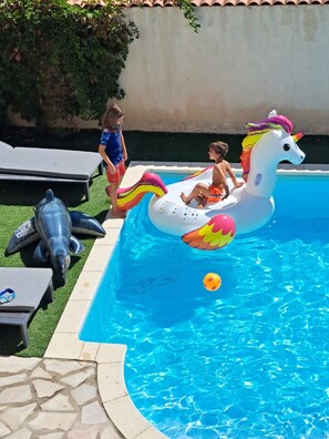 Piscina com brinquedos infláveis, incluindo um unicórnio e golfinhos.