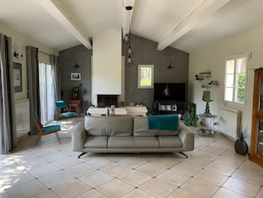 Uma sala de estar ampla com um sofá grande, lareira, televisão e estante de livros.