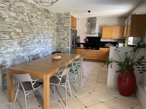 Uma cozinha moderna com painel de pedra, armários de madeira e uma área de refeições com mesa e cadeiras de madeira.