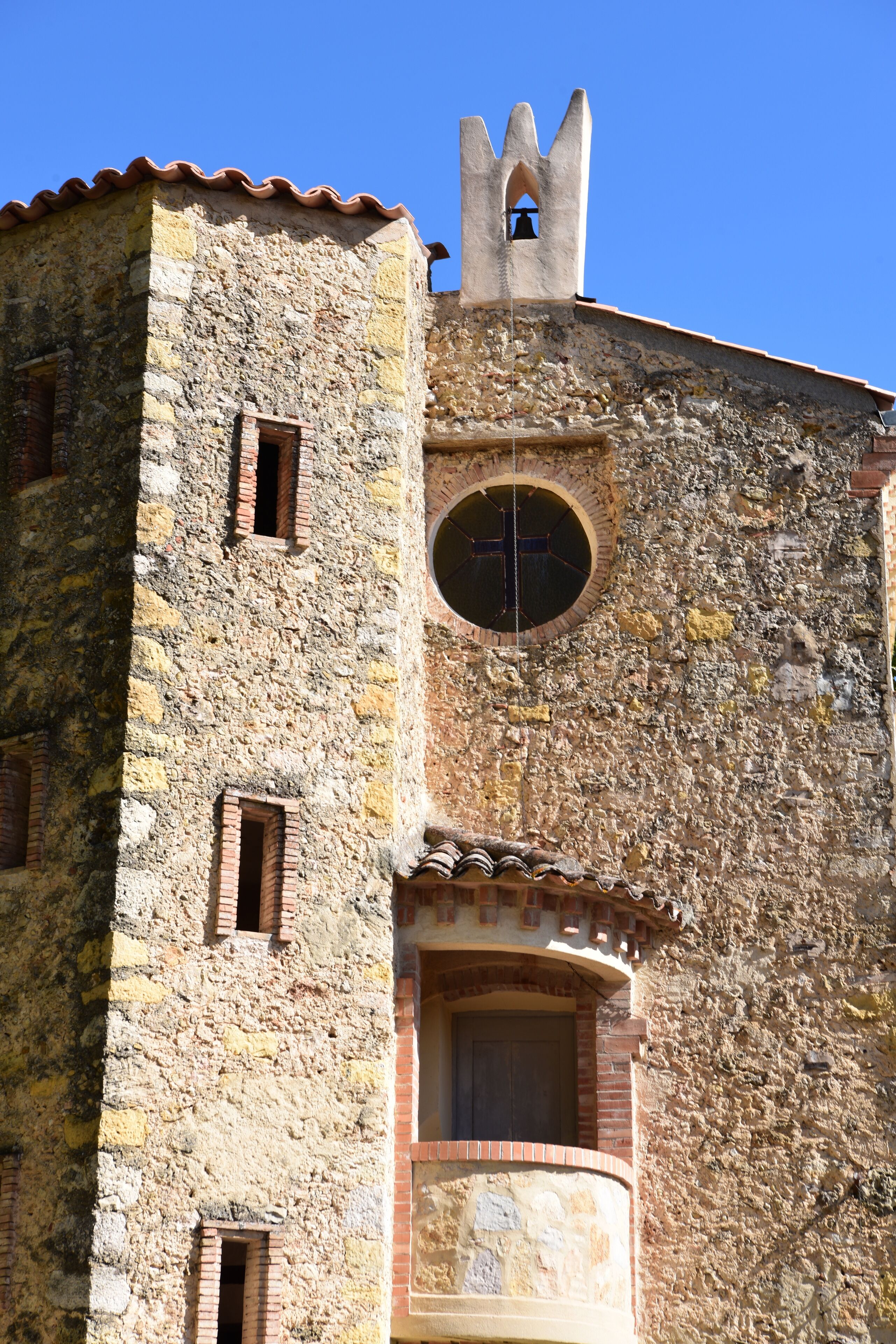 Ein historisches Steinhaus mit einem Glockenturm, zahlreichen Fenstern und einem Rundfenster.